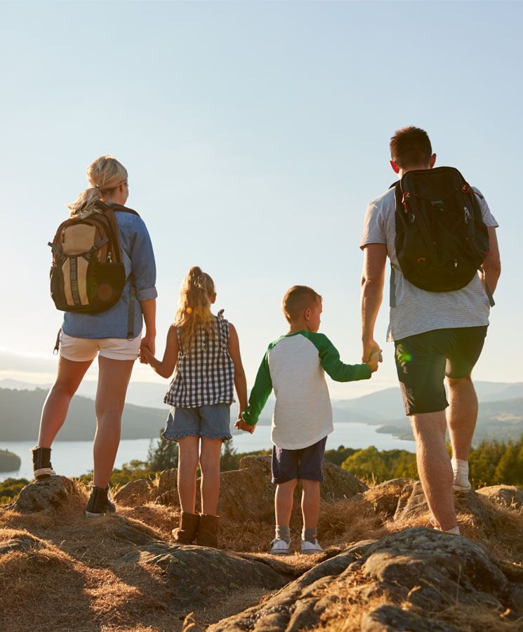 Rear View Of Family Standing At Top Of Hill On Hike Through Countryside In Lake District UK
